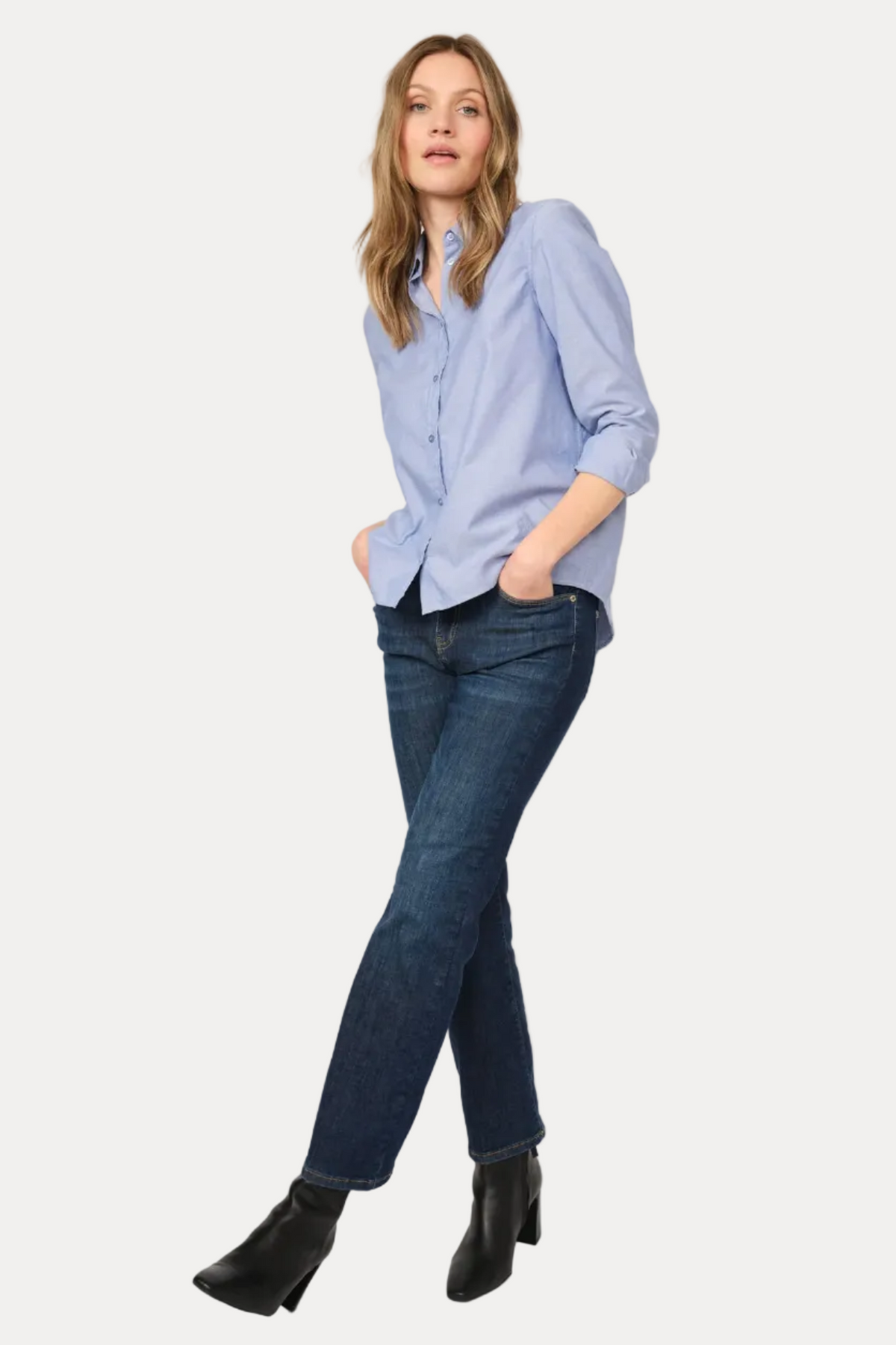 Woman wearing a light blue shirt and dark blue jeans on a white background