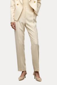 Woman wearing a beige suit standing against a plain background