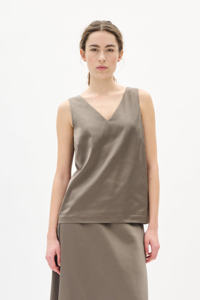 Woman wearing a sleeveless brown top and skirt set on a white background