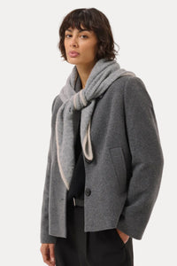 A model wearing a gray wool-blend coat with a matching gray knit scarf, styled with black trousers against a light gray studio background.