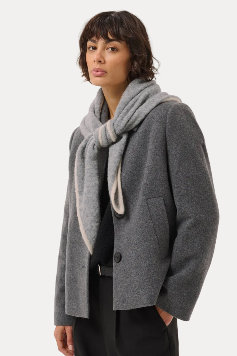 A model wearing a gray wool-blend coat with a matching gray knit scarf, styled with black trousers against a light gray studio background.