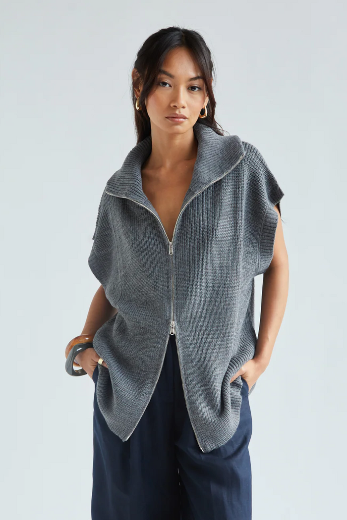 Woman wearing a gray knitted vest against a white background