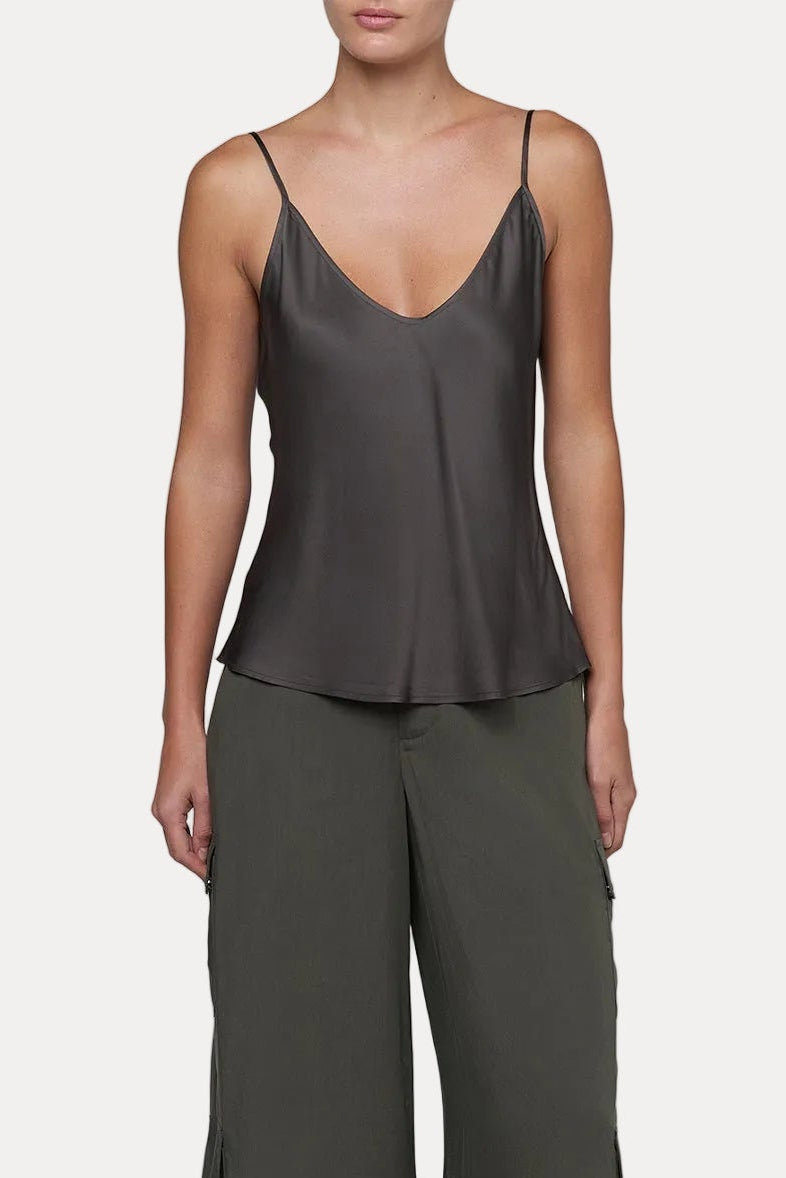Woman wearing a dark green slip top and wide-leg pants on a light gray background