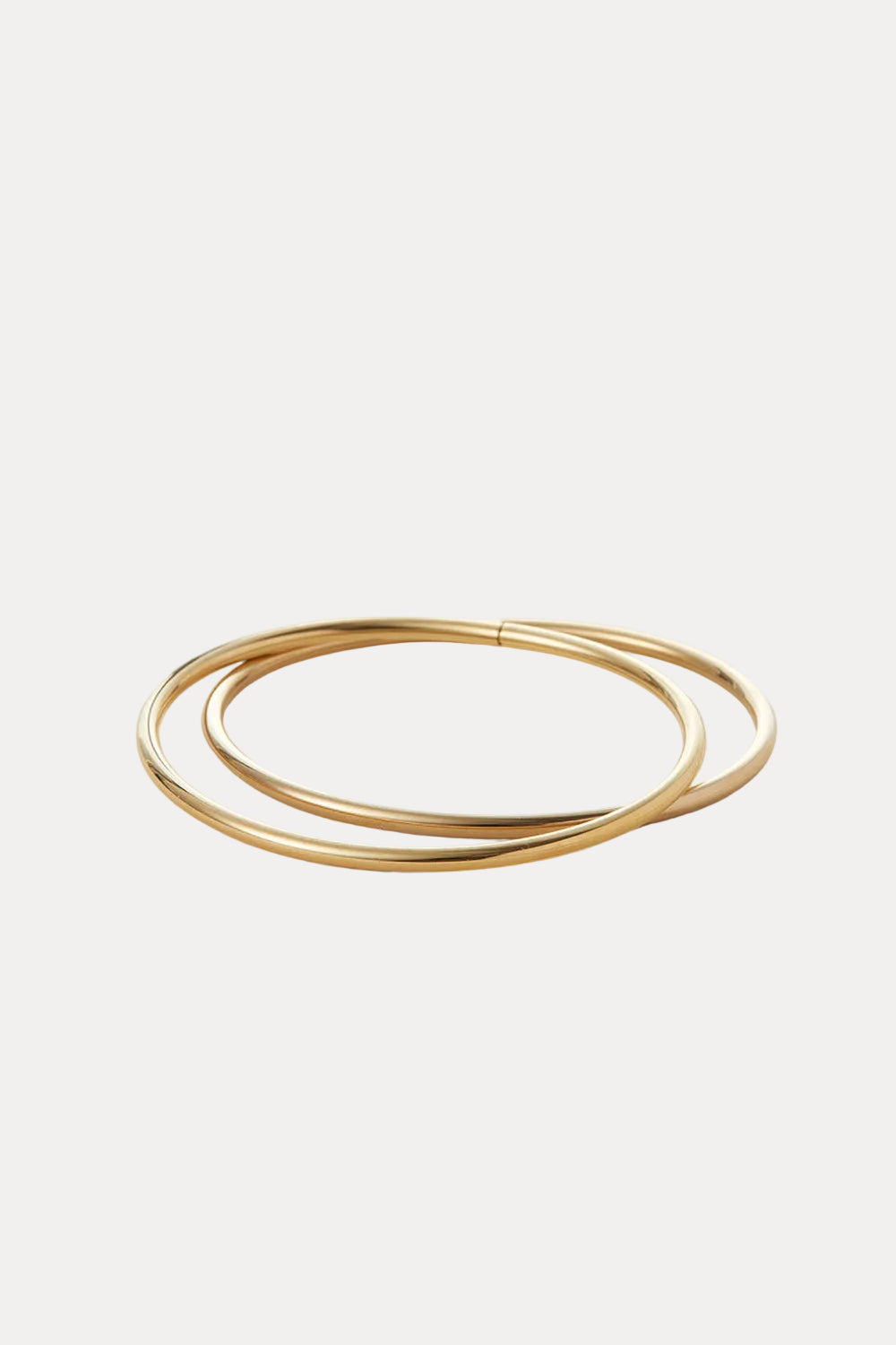 Set of gold bangles on a light beige background