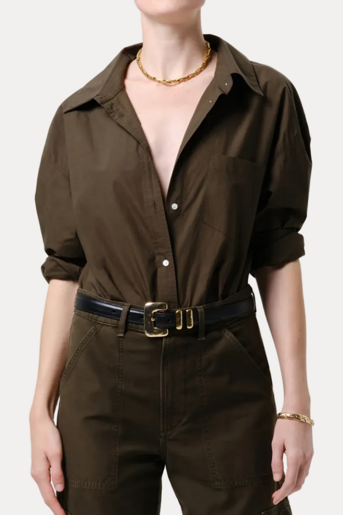 Person wearing a brown jumpsuit with a belt on a plain background