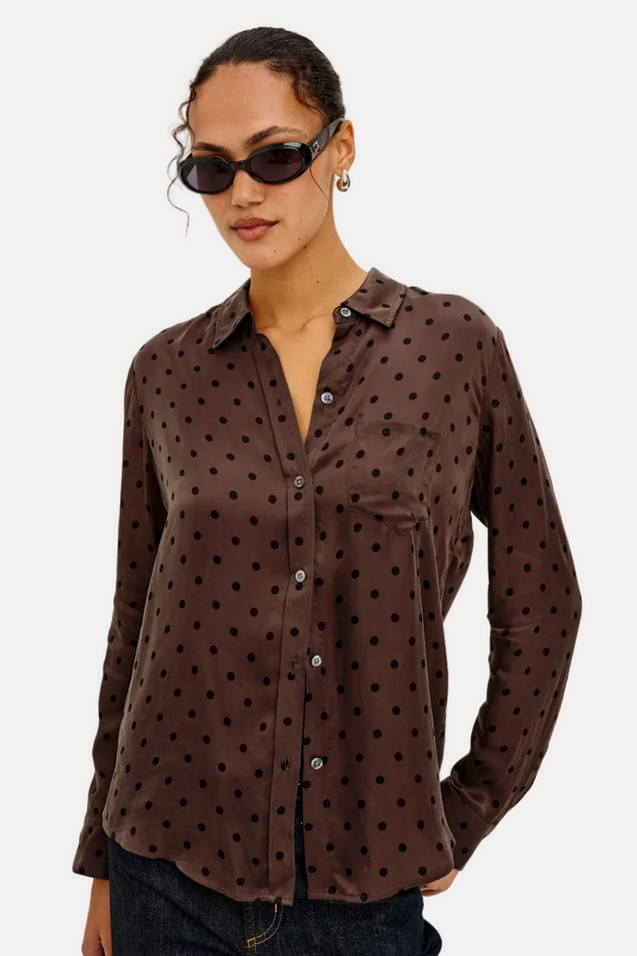 Woman wearing a brown polka dot shirt against a plain background