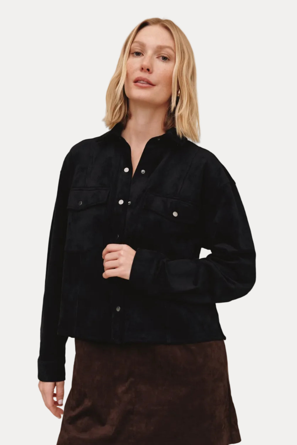 Woman wearing a black jacket and brown skirt on a beige background