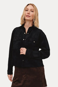 Woman wearing a black jacket and brown skirt on a beige background