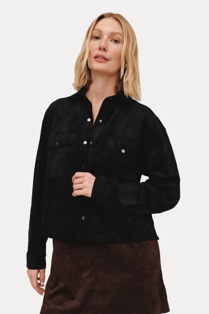 Woman wearing a black jacket and brown skirt on a beige background