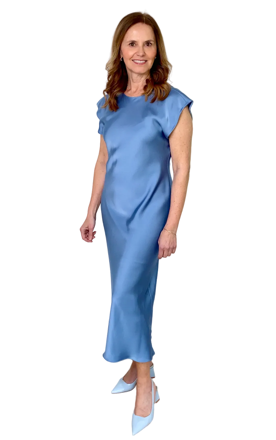 Woman wearing a blue dress standing against a white wall.