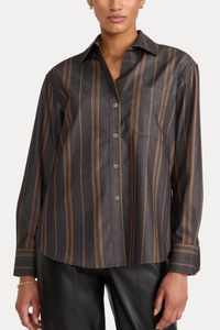 A woman wearing a dark charcoal gray button-down shirt with vertical tan stripes, paired with black leather pants, against a plain off-white background.
