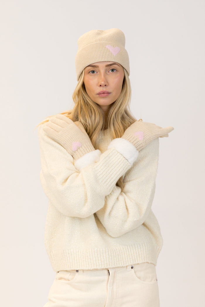 Woman wearing a cream-colored outfit with matching hat and gloves on a white background