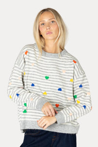 Woman wearing a gray striped sweater with colorful polka dots on a plain background
