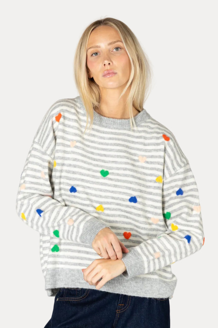 Woman wearing a gray striped sweater with colorful polka dots on a plain background