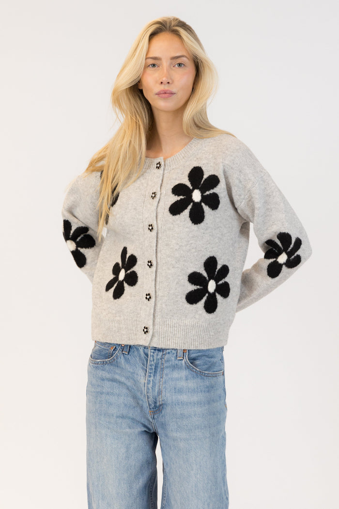 Woman wearing a gray cardigan with black floral patterns on a white background