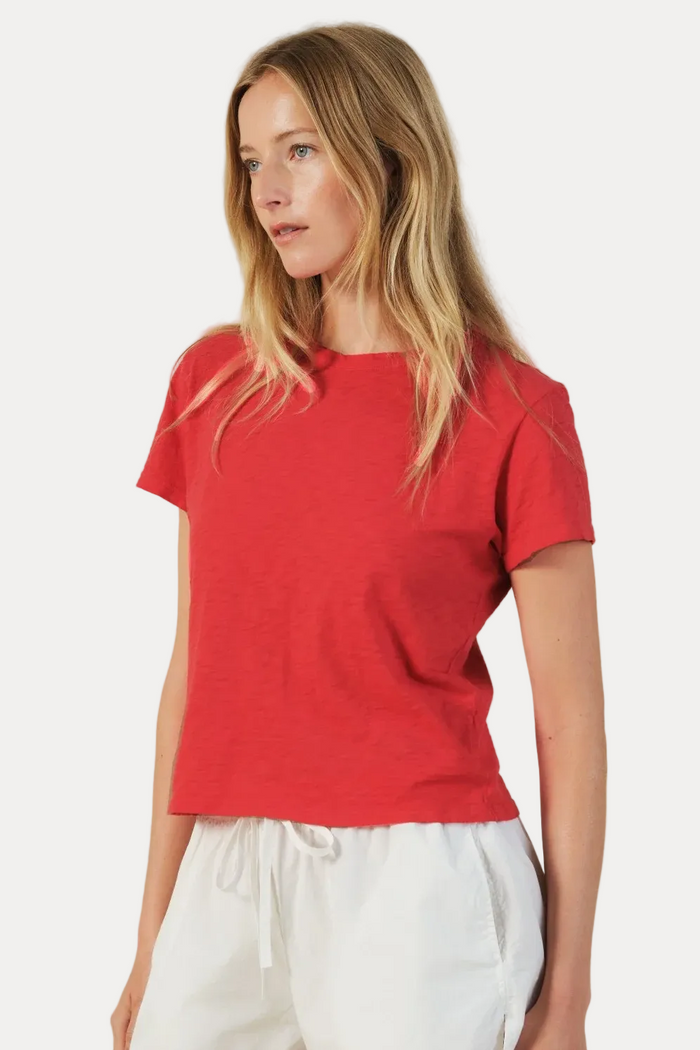 Woman wearing a red top and white shorts on a beige background