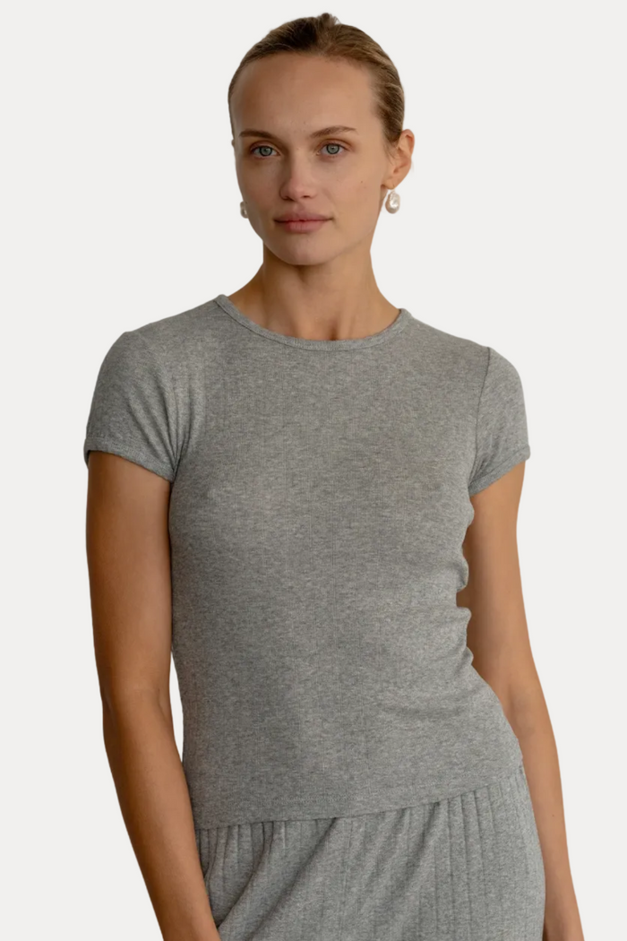 A woman modeling a short-sleeve crewneck t-shirt and matching relaxed-fit pants in a heather gray color, set against a plain light gray background.