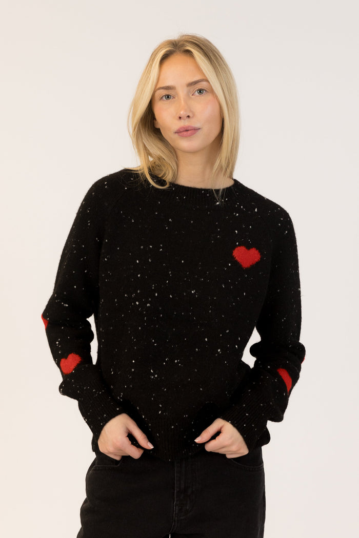 Woman wearing a black sweater with red heart patterns on a white background
