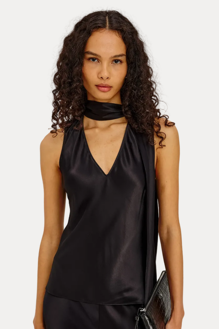 Woman wearing a black satin top and black pants against a plain background