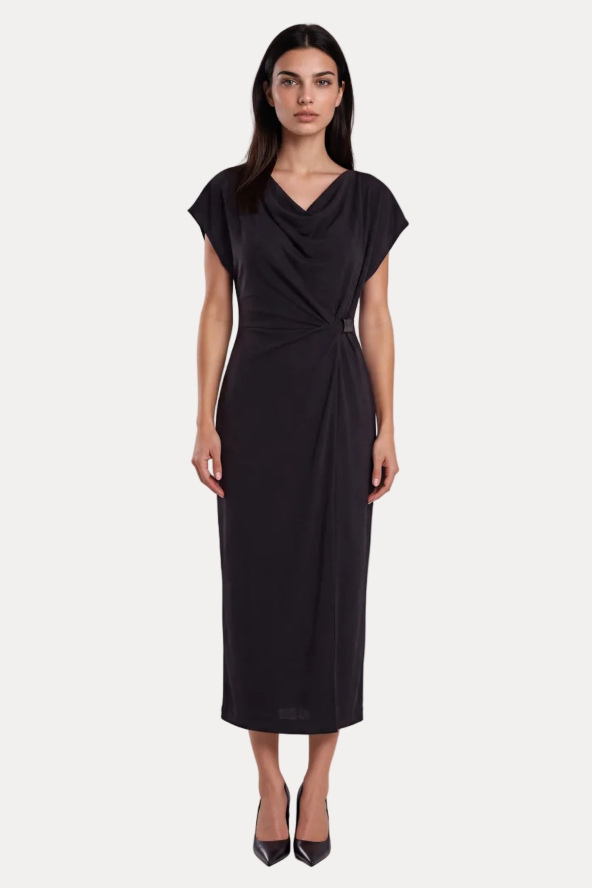 A woman modeling a black midi dress with a draped neckline, short cap sleeves, and a twisted waist detail, photographed against a light gray studio background.