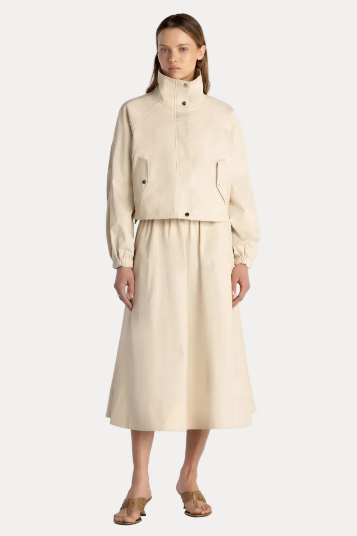 Woman wearing a beige outfit with a jacket and skirt on a white background