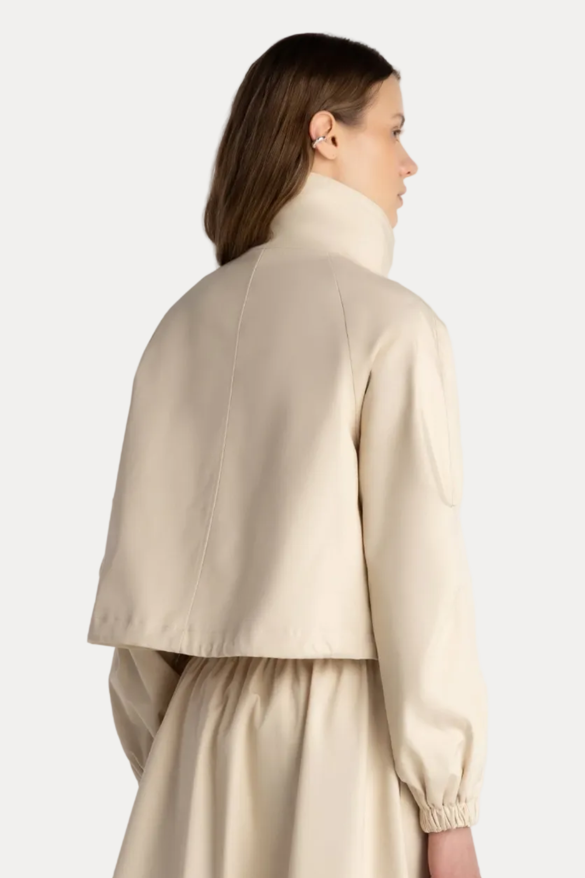 Woman wearing a beige jacket and dress against a white background