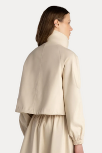 Woman wearing a beige jacket and dress against a white background