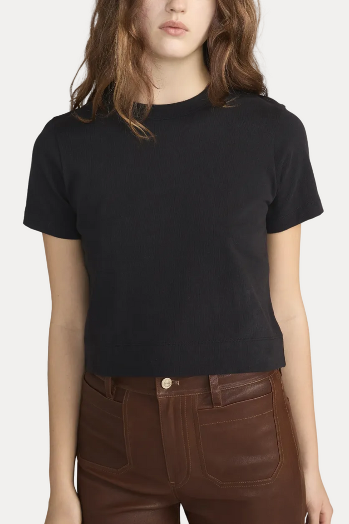 Person wearing a black t-shirt and brown pants on a white background