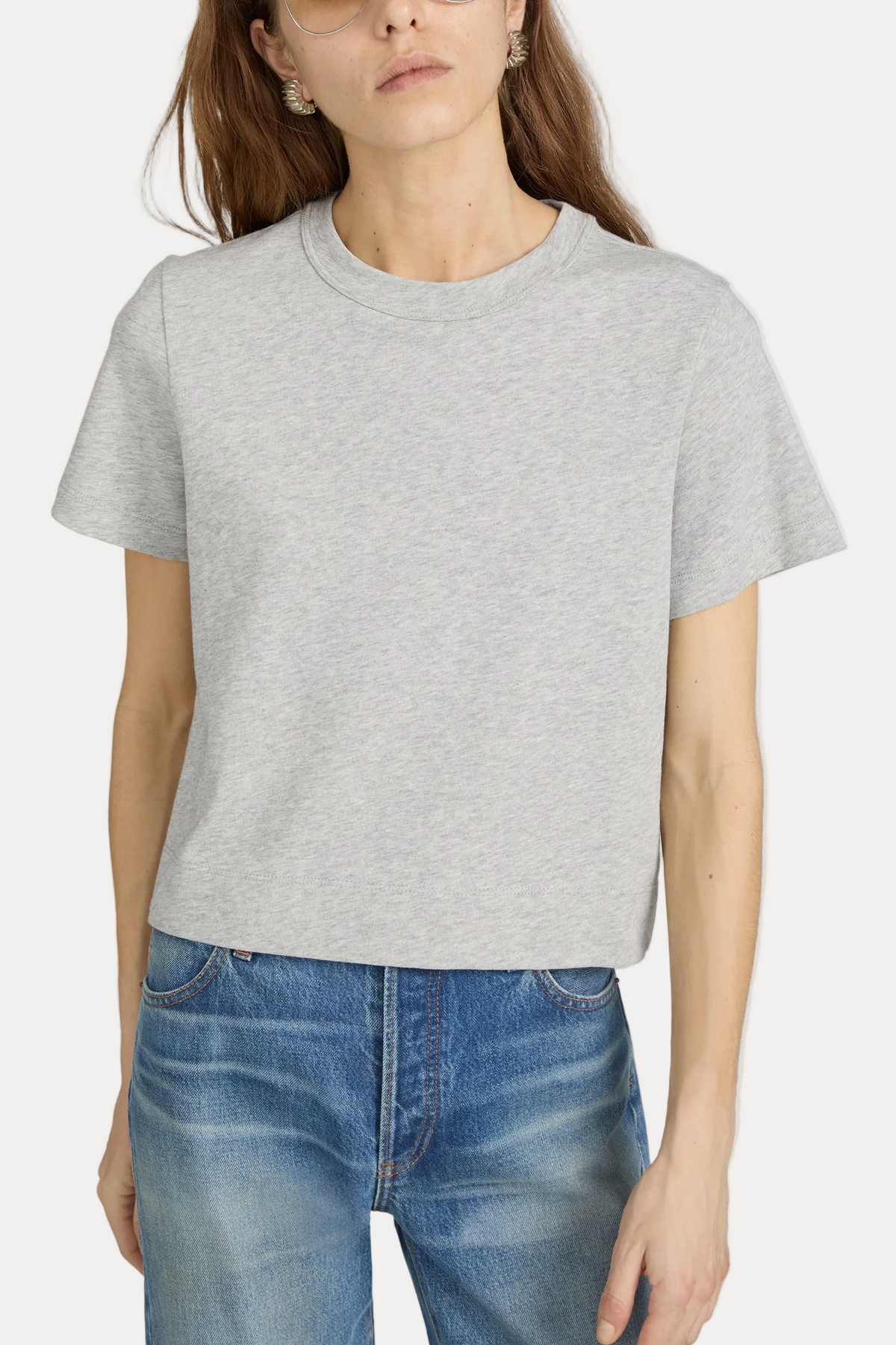 Person wearing a gray t-shirt and blue jeans on a plain background