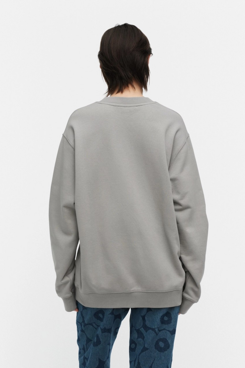 Person wearing a gray sweatshirt and blue patterned pants on a white background