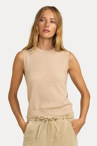 A woman modeling a sleeveless knit top in a light beige color, paired with beige drawstring pants, against a solid beige background.