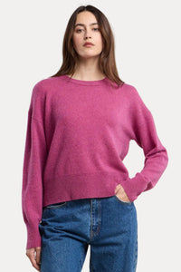 Woman wearing a pink sweater and blue jeans on a beige background