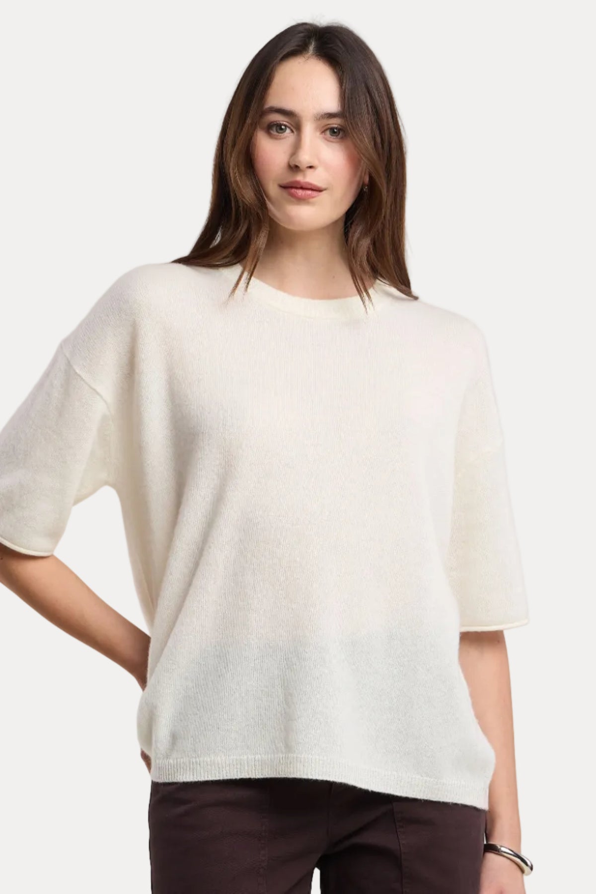 Woman wearing a white ombre top and dark pants on a beige background