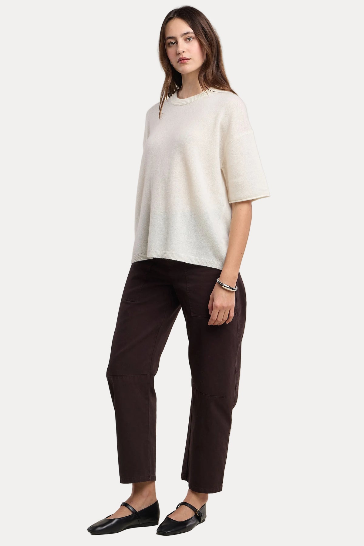 Woman wearing a white top and dark pants on a beige background