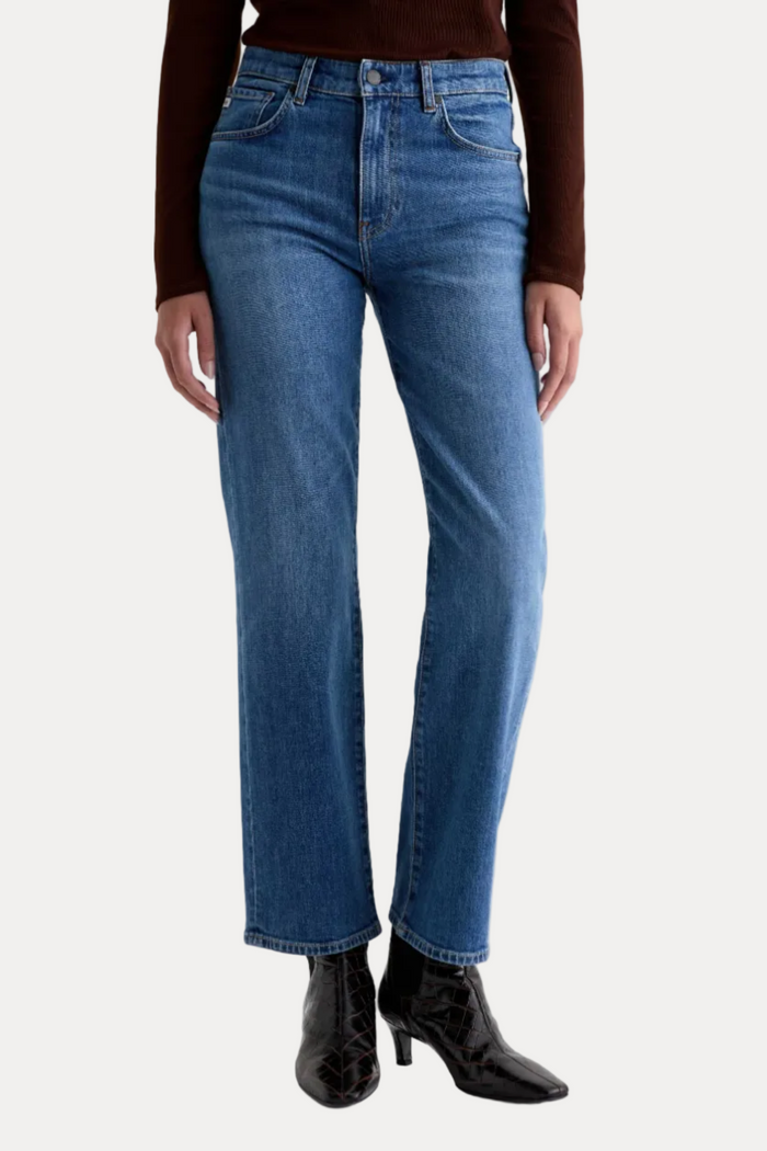 Person wearing blue jeans and black shoes on a white background