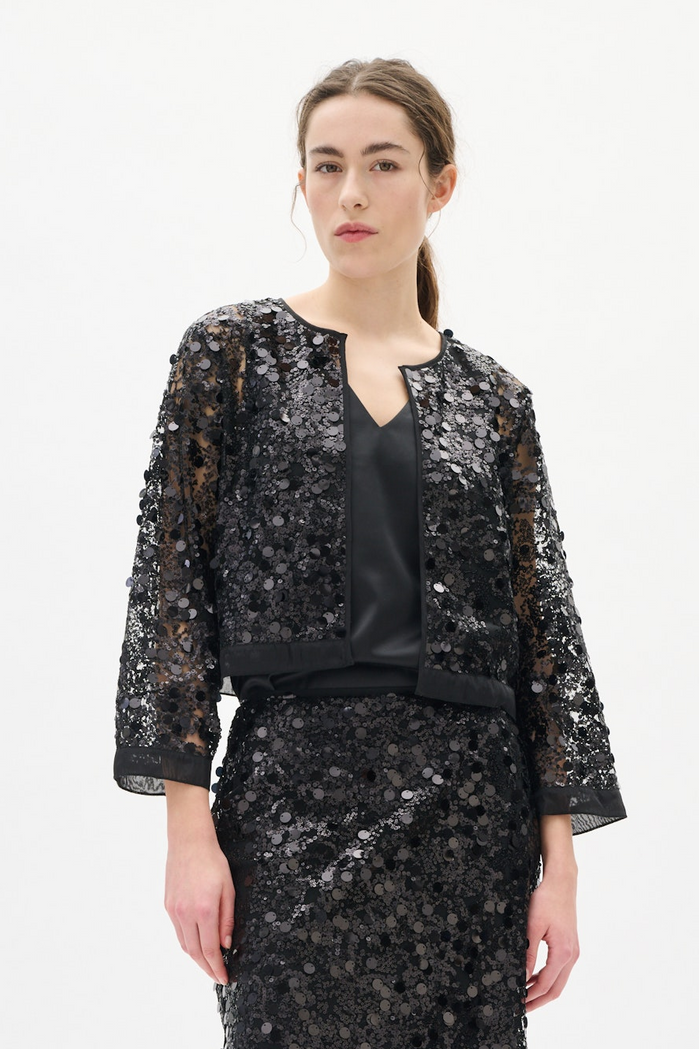 Woman wearing a black sequin outfit on a white background