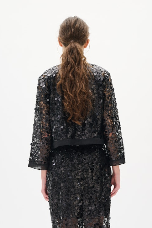 Person wearing a black sequin outfit on a white background