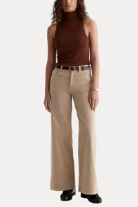 Woman wearing a brown turtleneck and beige wide-leg pants on a white background