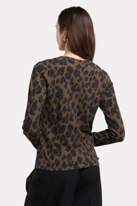 A woman shown from the back wearing a brown and black leopard print long-sleeve top with black pants, set against a plain beige studio background.