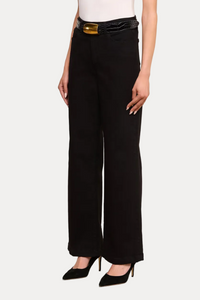 A model wearing black wide-leg trousers with a black belt featuring a gold buckle, styled with a white top and black pointed-toe heels against a plain white studio background.