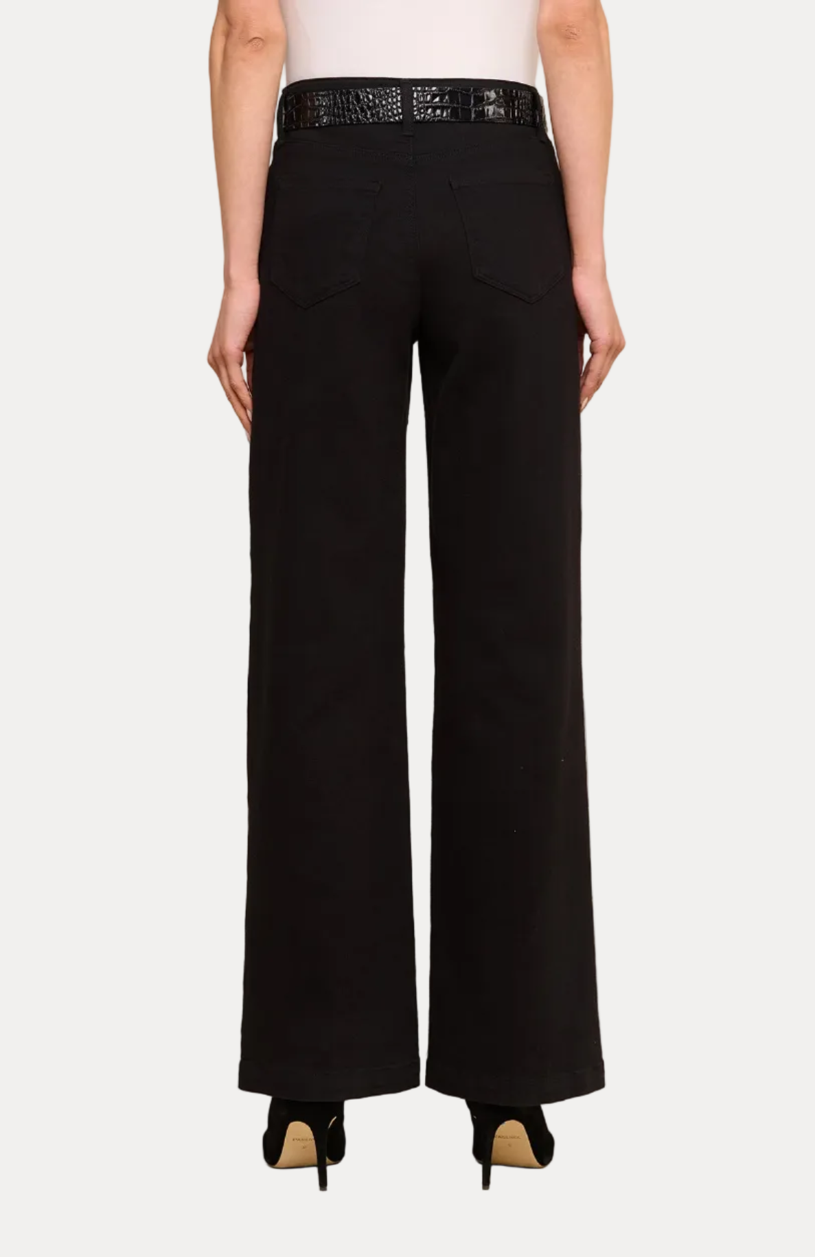 A model shown from the back wearing black wide-leg trousers, a black belt with silver studs, a white top, and black high heels against a plain white studio background.