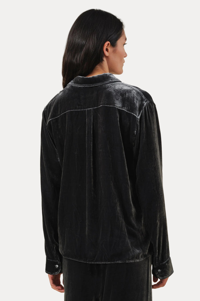 A model shown from the back wearing a black velvet long-sleeve shirt and matching black velvet pants against a plain light beige background.