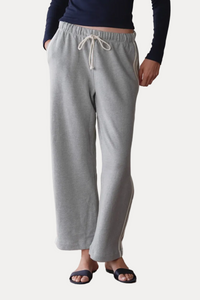 Woman wearing a navy long-sleeve top and gray sweatpants against a plain background