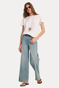 Woman wearing a white t-shirt and light blue jeans on a plain background
