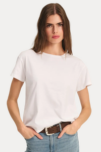 Woman wearing a plain white t-shirt and light blue jeans on a neutral background